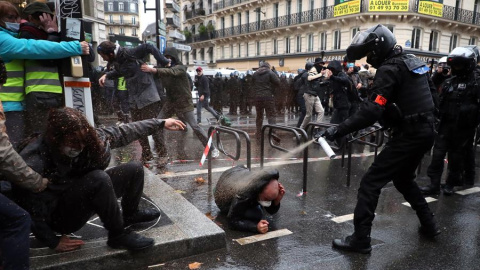 Un agente de policía francés echa spray sobre un manifestante en el suelo. Un agente de policía francés echa spray sobre un manifestante en el suelo.