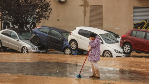 Una mujer realiza labores de limpieza junto a vehículos destrozados tras el paso de la DANA por el barrio de La Torre de València, a 30 de octubre de 2024. Una mujer realiza labores de limpieza junto a vehículos destrozados tras el paso de la DANA por el barrio de La Torre de València, a 30 de octubre de 2024.