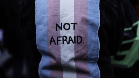 Imagen de archivo de una persona con un chaleco con una bandera trans en la espalda con las palabras "Sin miedo" Imagen de archivo de una persona con un chaleco con una bandera trans en la espalda con las palabras "Sin miedo"