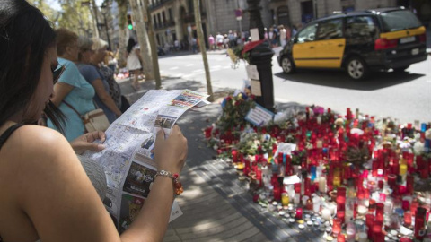 Una joven consulta un plano ante una de las ofrendas en las Ramblas cuatro días después de los atentados. EFE/Marta Pérez Una joven consulta un plano ante una de las ofrendas en las Ramblas cuatro días después de los atentados. EFE/Marta Pérez