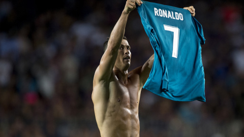 El jugador del Real Madrid Cristiano Ronaldo muestra su camiseta a los aficionados del Nou Camp, tras marcar el 1-2 de la ida de la Supercopa, lo que le valió la primera tarjeta amarilla. STRINGER / AFP