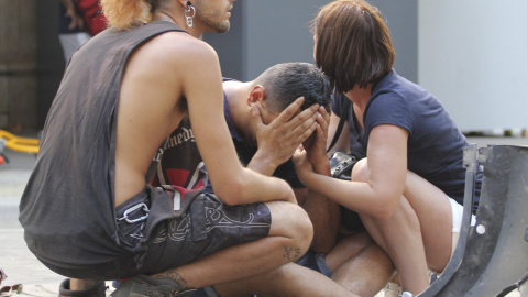 Varios jóvenes permanecen junto a los restos de un vehículo, en el lugar del atropello masivo de una furgoneta que ha arrollado esta tarde a varias personas que paseaban por las Ramblas de Barcelona.- EFE