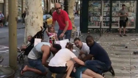 Varias personas ayudan a una de las víctimas del atentado en Barcelona.- REUTERS