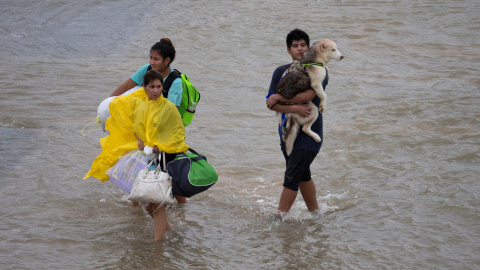 Una familia lleva sus pertenencias y su perro mientras es evacuada por las inundaciones de la tormenta tropical Harvey, en Houston, Texas, (EEUU).- REUTERS/ Adrees Latif