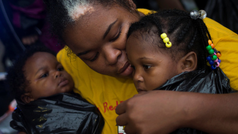 Laquanta Edwards sostiene a su hija de un año Ladaja (D) y a su hijo LaDarius, de nueve meses, después de ser evacuados a tierras altas en barco debido a las inundaciones causadas por la tormenta tropical Harvey a lo largo de Tidwell Road en Houston est