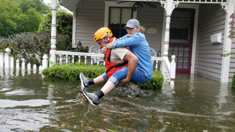 Un guarda ayuda a una mujer en las inundaciones en Houston por Harvey. REUTERS Un guarda ayuda a una mujer en las inundaciones en Houston por Harvey. REUTERS