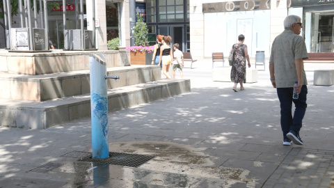Un home d'edat avançada camina amb una ampolla d'aigua a la mà vora d'una font prop de l'Eix Comercial a Lleida Un home d'edat avançada camina amb una ampolla d'aigua a la mà vora d'una font prop de l'Eix Comercial a Lleida