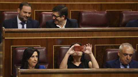 La diputada socialista Adriana Lastra, toma fotos con su móvil del hemicíclo del Congreso de los Diputados. A la izquierda, la portavoz del PSOE, margarita Robles y a la derecha, Rafael Simancas. EFE/Mariscal