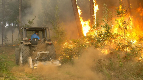 Un hombre subido en un tractor se sitúa frente al fuego del incendio de Zamanes, Vigo. EFE/Salvador Sas Un hombre subido en un tractor se sitúa frente al fuego del incendio de Zamanes, Vigo. EFE/Salvador Sas