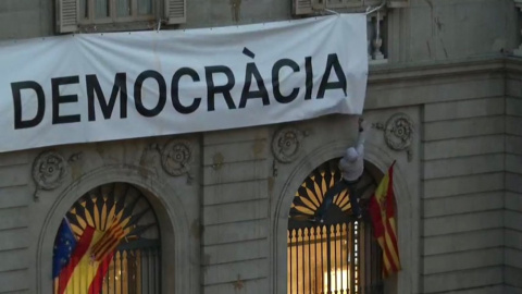 Moment en què uns encaputxats intententen despenjar la pancarta amb l'expressió 'Més democràcia' de la façana de l'Ajuntament Moment en què uns encaputxats intententen despenjar la pancarta amb l'expressió 'Més democràcia' de la façana de l'Ajuntament