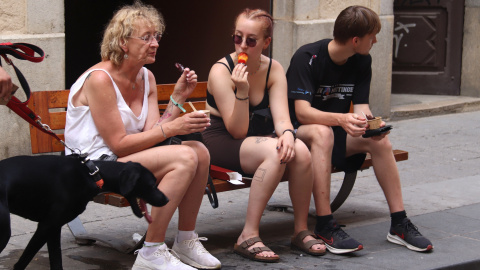 Tres turistes es mengen un gelat al carrer de Santa Clara de Girona Tres turistes es mengen un gelat al carrer de Santa Clara de Girona