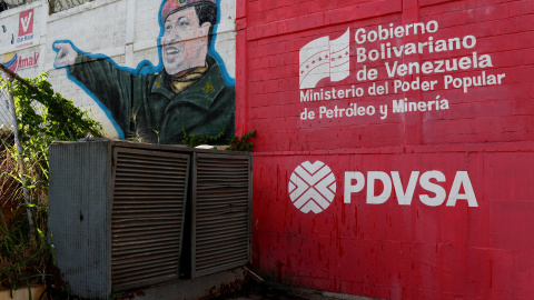 El logo de la compañía estatal venezolana de petroleo, PDVSA, junto a un mural de Hugo Chávez.REUTERS/Carlos García Rawlins