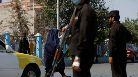Una mujer afgana camina entre talibanes en un puesto de control en Mazar-i-Sharif, Afganistán, a 6 de agosto de 2023. Una mujer afgana camina entre talibanes en un puesto de control en Mazar-i-Sharif, Afganistán, a 6 de agosto de 2023.