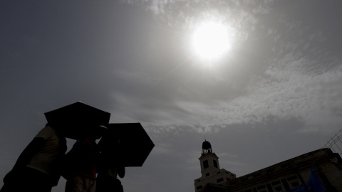 Varios viandantes se protegen del sol mientras cruzan la Puerta del Sol de Madrid. Varios viandantes se protegen del sol mientras cruzan la Puerta del Sol de Madrid.