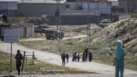 Tanques israelíes patrulla mientras los palestinos desplazados internos caminan hacia Rafah. Tanques israelíes patrulla mientras los palestinos desplazados internos caminan hacia Rafah.