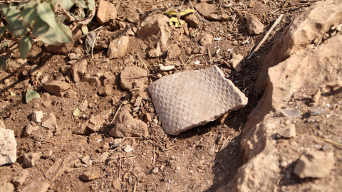 Un tros d'amiant enmig de la sorra i les pedres a la zona de les bateries del Turó de la Rovira Un tros d'amiant enmig de la sorra i les pedres a la zona de les bateries del Turó de la Rovira