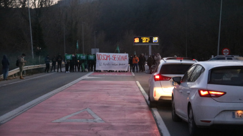 Els manifestants al fons protestant mentre els conductors esperen aturats pel tall de la carretera a Ripoll. Els manifestants al fons protestant mentre els conductors esperen aturats pel tall de la carretera a Ripoll.