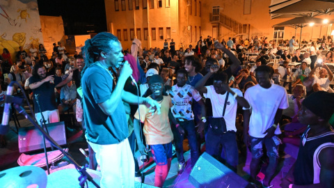 Migrantes recién desembarcados, vecinos y turistas cantan y bailan en una plaza de Lampedusa (Italia), donde han llegado 10.000 migrantes en apenas tres días. Migrantes recién desembarcados, vecinos y turistas cantan y bailan en una plaza de Lampedusa (Italia), donde han llegado 10.000 migrantes en apenas tres días.