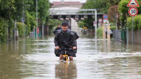 Un hombre monta en bicicleta en mitad de las inundaciones provocadas por las lluvias torrenciales de mayo en Emilia-Romagna, en Italia. Un hombre monta en bicicleta en mitad de las inundaciones provocadas por las lluvias torrenciales de mayo en Emilia-Romagna, en Italia.
