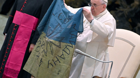 12/04/2022 - El papa Francisco muestra una bandera de Ucrania que fue enviada desde la localidad de Bucha durante la audiencia semanal en el Salón de Pablo VI en el Vaticano. 12/04/2022 - El papa Francisco muestra una bandera de Ucrania que fue enviada desde la localidad de Bucha durante la audiencia semanal en el Salón de Pablo VI en el Vaticano.