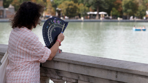 Una mujer combate el calor con un abanico mientras observa el lago del Parque del Retiro de Madrid. Una mujer combate el calor con un abanico mientras observa el lago del Parque del Retiro de Madrid.