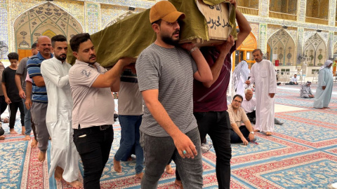 Chiíes llevan a un fallecido ante la tumba de Ali, hijo del profeta Mahoma, antes de ser enterrado en el cementerio de Nayaf (Irak). En este lugar descansan muchos iraquíes muertos durante la guerra contra el Estado Islámico.