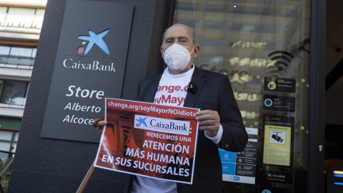 Carlos San Juan, el hombre de 78 años que ha recogido más de 600.000 apoyos con su campaña 'Soy Mayor, No Idiota', posa delante de una sucursal bancaria con un cartel que simula la entrega de sus firmas a los bancos, tras registrarlas en el Ministerio Carlos San Juan, el hombre de 78 años que ha recogido más de 600.000 apoyos con su campaña 'Soy Mayor, No Idiota', posa delante de una sucursal bancaria con un cartel que simula la entrega de sus firmas a los bancos, tras registrarlas en el Ministerio