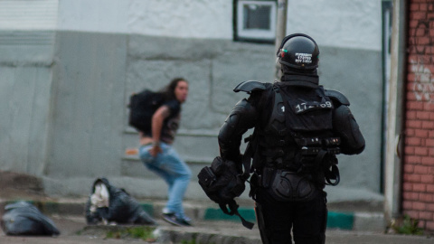 Un policía antidisturbios persigue a un manifestante durante una protesta contra el proyecto de ley de reforma fiscal propuesto por el gobierno de Colombia. Un policía antidisturbios persigue a un manifestante durante una protesta contra el proyecto de ley de reforma fiscal propuesto por el gobierno de Colombia.
