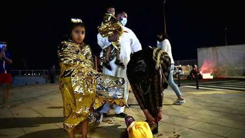 Un hombre migrante coge en brazos a un menor acompañado de una mujer y una niña pequeña, a 17 de mayo de 2021, en Ceuta