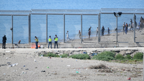 Agentes vigilan desde la valla que separa Ceuta de Marruecos la llegada de migrantes, a 19 de mayo de 2021, en Ceuta