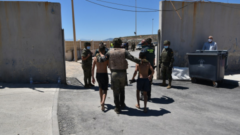 Un militar del ejército español y un agente de la Guardia Civil ayudan a dos menores migrantes procedentes de Marruecos a su llegada a Ceuta, a 19 de mayo