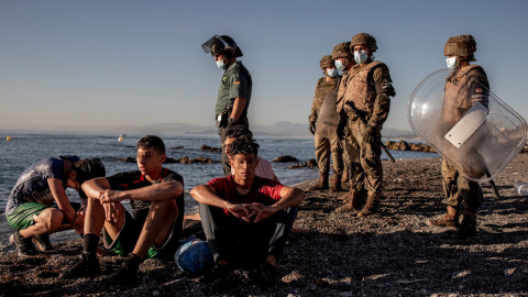 Miembros del ejército observan a un grupo de inmigrantes menores a su llegada a la playa de El Tarajal en Ceuta.