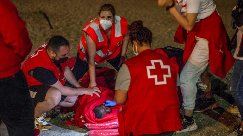 Efectivos de Cruz Roja atienden a un migrante con signos de hipotermia tras intentar cruzar a España por el agua en la playa de El Tarajal este miércoles 19 de mayo de 2021.