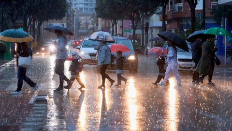 Varias personas cruzan una calle en Valencia bajo la lluvia. Varias personas cruzan una calle en Valencia bajo la lluvia.