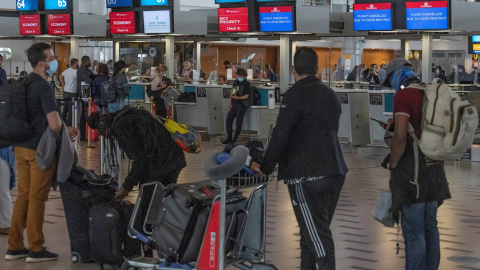 Varios pasajeros miran las pantallas de información en el aeropuerto de Ciudad del Cabo, en Sudáfrica.