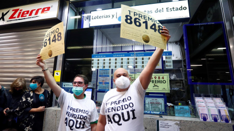 Los loteros de la administración de Madrid donde ha tocado el Gordo del sorteo de la lotería de Navidad muestra el cartel con el número 86.148 agraciado con el primer premio. Los loteros de la administración de Madrid donde ha tocado el Gordo del sorteo de la lotería de Navidad muestra el cartel con el número 86.148 agraciado con el primer premio.