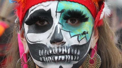 La calavera es retratada del pecho hacia arriba con una expresión de felicidad en el rostro y ataviada con un amplio sombrero adornado con plumas y flores. EFE/ Mario Guzmán