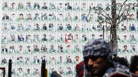 Los yemeníes se paran frente a una enorme pancarta que muestra los retratos de los combatientes hutíes presuntamente asesinados en el conflicto en curso, en una calle antes del séptimo aniversario de la campaña militar dirigida por Arabia Saudita en Y Los yemeníes se paran frente a una enorme pancarta que muestra los retratos de los combatientes hutíes presuntamente asesinados en el conflicto en curso, en una calle antes del séptimo aniversario de la campaña militar dirigida por Arabia Saudita en Y