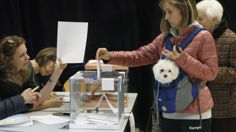 Una mujer vota acompañada de su mascota en un local electoral de Barcelona. EFE/ Andreu Dalmau