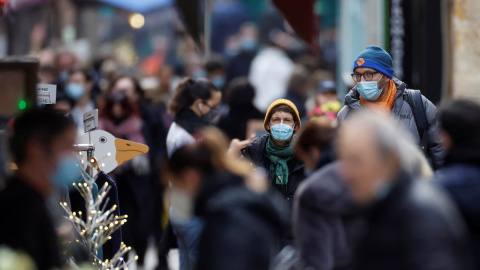 Personas, con máscaras protectoras, caminan por la calle Mouffetard, en medio de la propagación de la pandemia en París, Francia, 30 de diciembre de 2021. Personas, con máscaras protectoras, caminan por la calle Mouffetard, en medio de la propagación de la pandemia en París, Francia, 30 de diciembre de 2021.