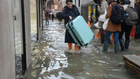 Una turista carga su maleta con ruedas para evitar que toque el "agua alta" en Venecia (Italia), este viernes. EFE/Andrea Merola Una turista carga su maleta con ruedas para evitar que toque el "agua alta" en Venecia (Italia), este viernes. EFE/Andrea Merola