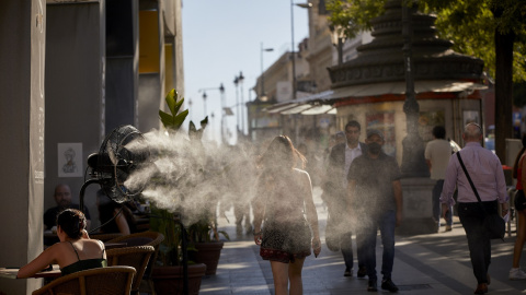 Varias personas caminan al lado de un difusor de vapor de agua de un restaurante en Madrid, en una imagen del 2 de julio de 2021. Varias personas caminan al lado de un difusor de vapor de agua de un restaurante en Madrid, en una imagen del 2 de julio de 2021.