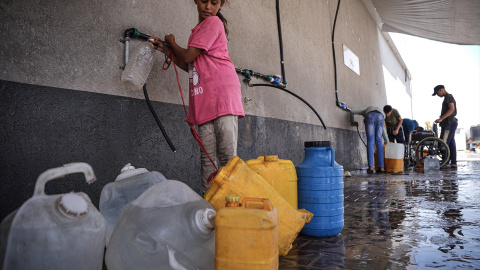 Foto de archivo de una niña palestina llenando garrafas de agua. Foto de archivo de una niña palestina llenando garrafas de agua.