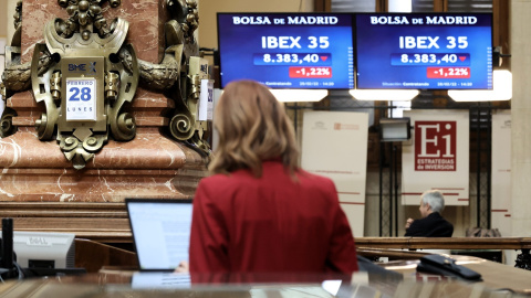 Una mujer consulta los valores del Ibex 35 en los paneles del Palacio de la Bolsa de Madrid