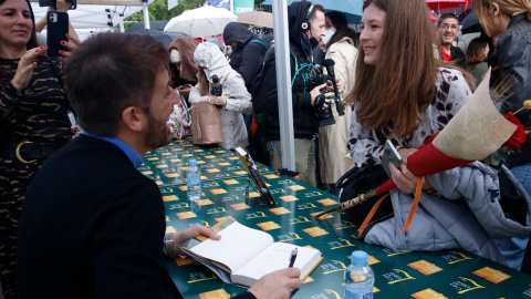 El periodista Toni Cruanyes signa un llibre mentre conversa amb una lectora.