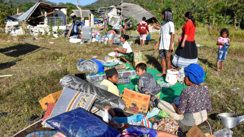Los residentes en Indonesia esperan fuera de sus casa con todas las pertenencias que han podido salvar tras el terremoto. / Reuters