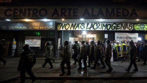 Un grupo de Fuerzas Especiales de Carabineros camina frente al cine Arte Alameda custodiado por voluntarios sanitarios el pasado viernes 13 de diciembre. /EFE Un grupo de Fuerzas Especiales de Carabineros camina frente al cine Arte Alameda custodiado por voluntarios sanitarios el pasado viernes 13 de diciembre. /EFE