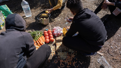 Varios chavales marroquíes preparan la comida en uno de los bosques de Ceuta, donde viven tras la crisis fronteriza de 2021.