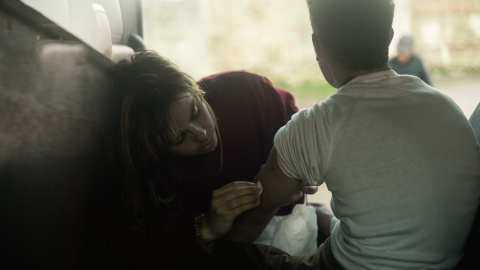 Una voluntaria de la organización No Name Kitchen desinfecta una herida a uno de los chavales que aún quedan en las calles de Ceuta un año después de que Marruecos permitiera el cruce irregular de la frontera.