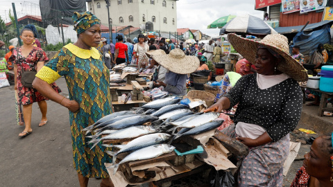 Una mujer habla con una vendedora de pescado en un mercado de Lagos, Nigeria Una mujer habla con una vendedora de pescado en un mercado de Lagos, Nigeria